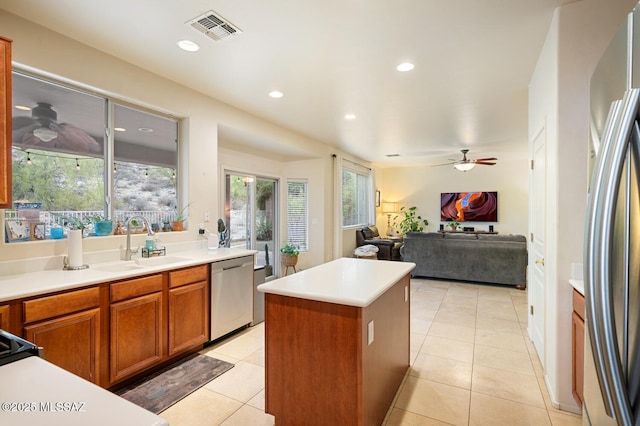 kitchen with stainless steel appliances, a sink, a ceiling fan, visible vents, and a center island