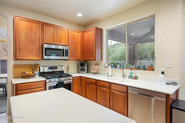 kitchen featuring stainless steel appliances, brown cabinetry, a sink, and light countertops