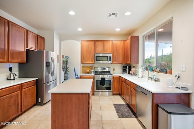 kitchen featuring visible vents, a kitchen island, stainless steel appliances, a sink, and light tile patterned flooring