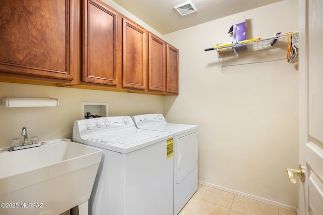 clothes washing area featuring light tile patterned floors, washing machine and dryer, a sink, visible vents, and cabinet space