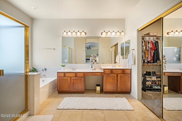 full bath with double vanity, a stall shower, a garden tub, tile patterned flooring, and a sink