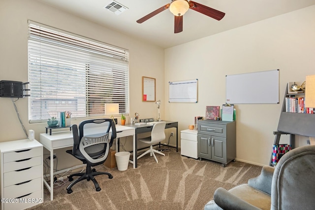 office featuring baseboards, visible vents, a ceiling fan, and light colored carpet