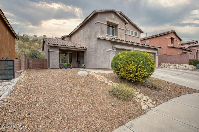 view of front of home with a garage, fence, concrete driveway, a tiled roof, and stucco siding