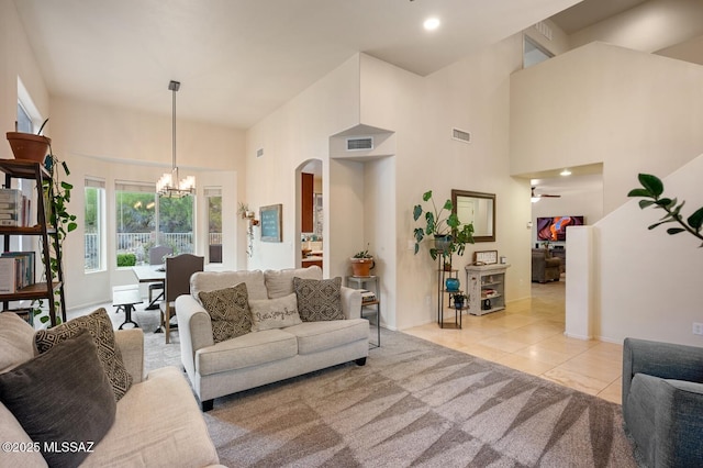 living room featuring light tile patterned floors, arched walkways, visible vents, and an inviting chandelier