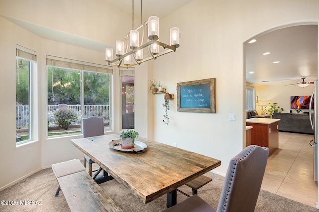 dining room featuring arched walkways, light tile patterned floors, light colored carpet, recessed lighting, and baseboards