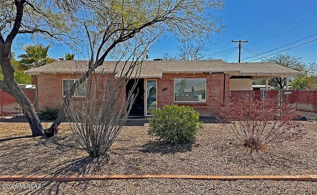 ranch-style home featuring brick siding and fence