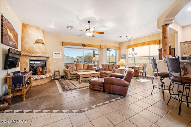 living room featuring ceiling fan, tile patterned flooring, a large fireplace, visible vents, and ornate columns