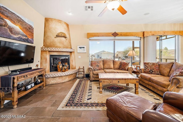 living room featuring ceiling fan, stone finish floor, a fireplace, and visible vents