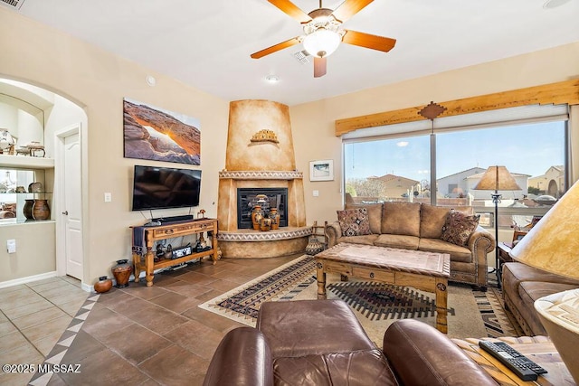 living room with a large fireplace, a ceiling fan, visible vents, and baseboards