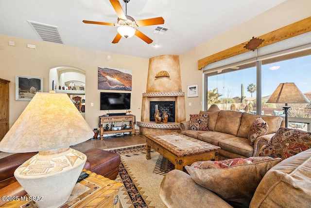 living room featuring a large fireplace, tile patterned flooring, visible vents, and a ceiling fan