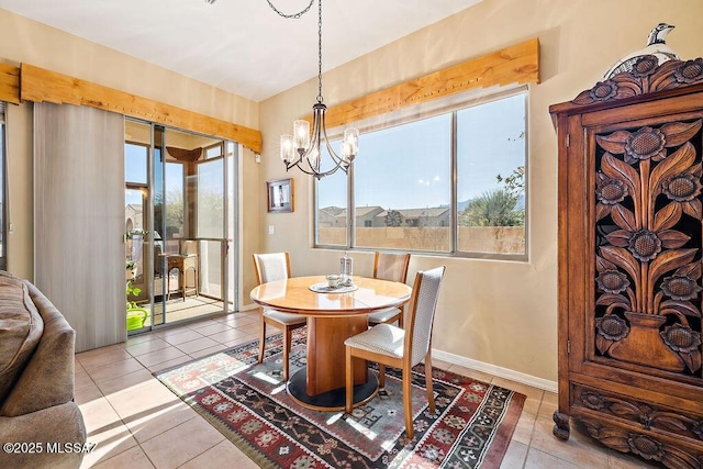 dining room with a chandelier, baseboards, and tile patterned floors