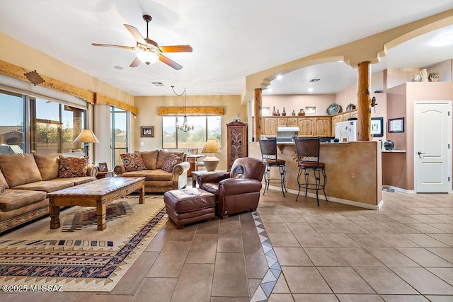 living area with light tile patterned floors, ceiling fan, decorative columns, and baseboards