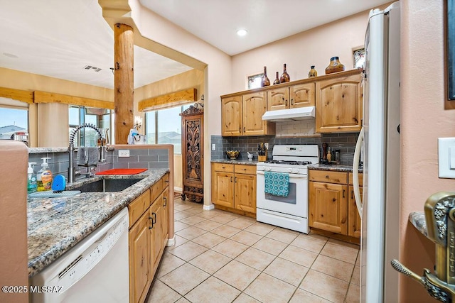 kitchen with under cabinet range hood, white appliances, a sink, visible vents, and backsplash