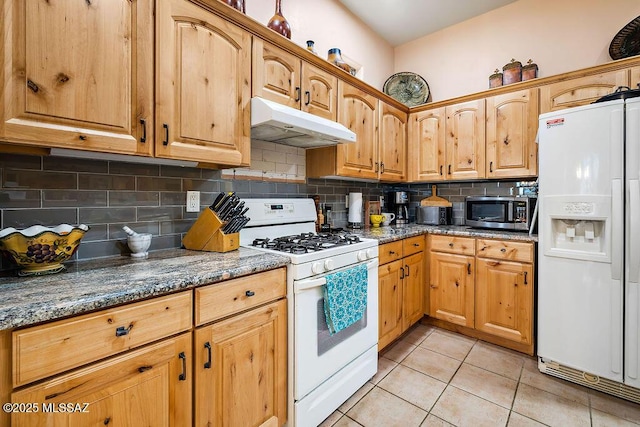 kitchen with stone counters, light tile patterned floors, tasteful backsplash, white appliances, and under cabinet range hood