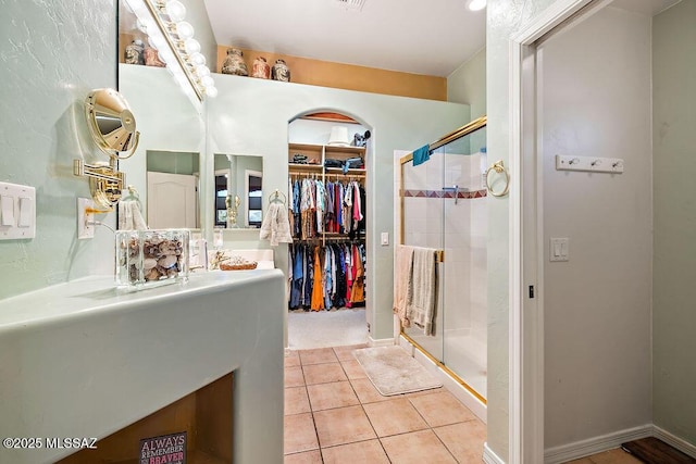 bathroom featuring a stall shower, tile patterned flooring, a walk in closet, and vanity