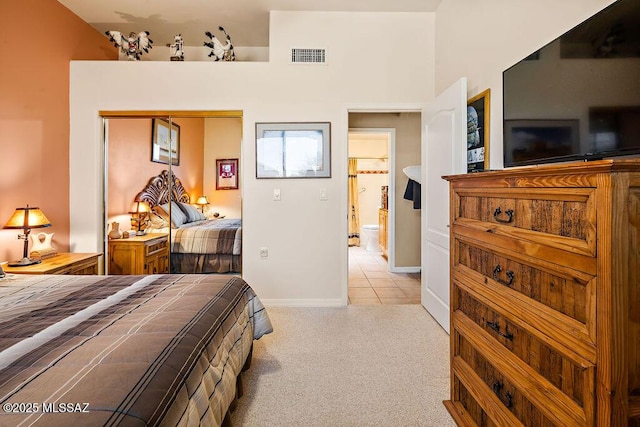 bedroom with light tile patterned floors, baseboards, visible vents, light colored carpet, and a closet