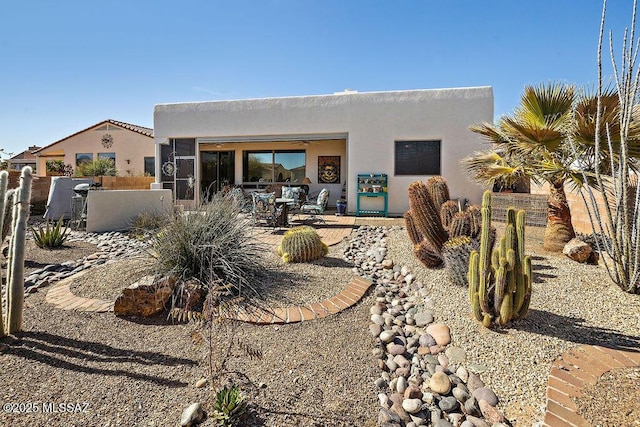 rear view of house featuring a patio, fence, and stucco siding