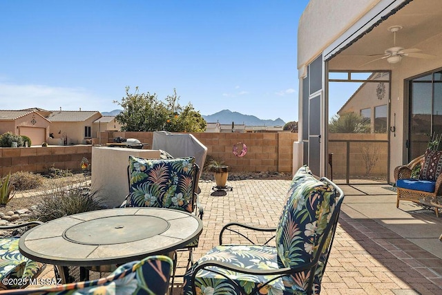 view of patio / terrace with ceiling fan, fence, and a mountain view