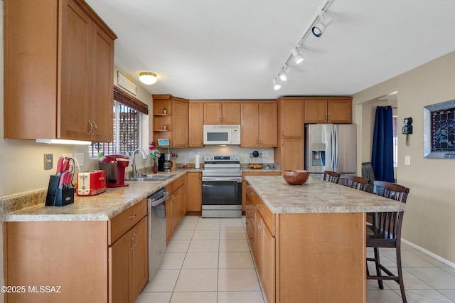 kitchen featuring a kitchen bar, stainless steel appliances, a sink, and light countertops