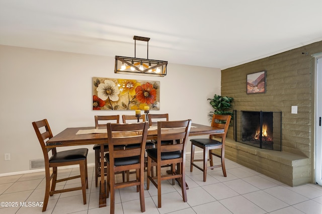 dining area featuring visible vents, a fireplace, light tile patterned flooring, and baseboards