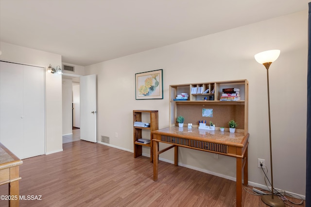 home office with visible vents, light wood-style flooring, and baseboards