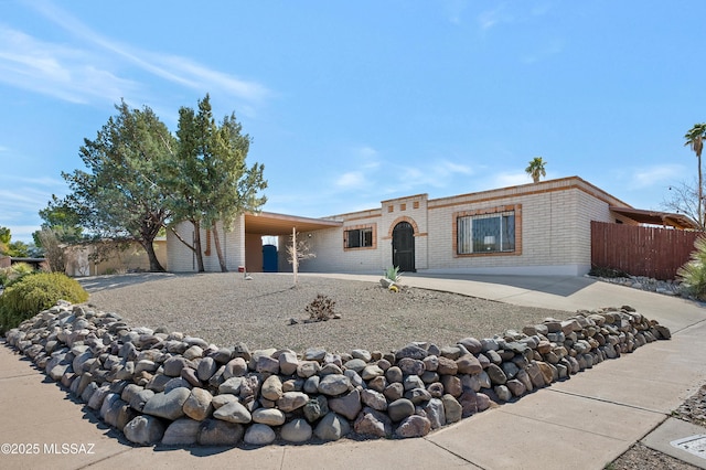 ranch-style house featuring an attached carport, fence, and driveway