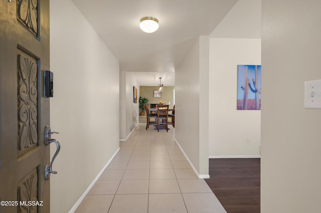 corridor featuring light tile patterned floors and baseboards