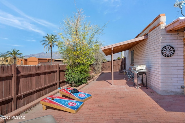 view of patio / terrace with area for grilling, a fenced backyard, and a mountain view