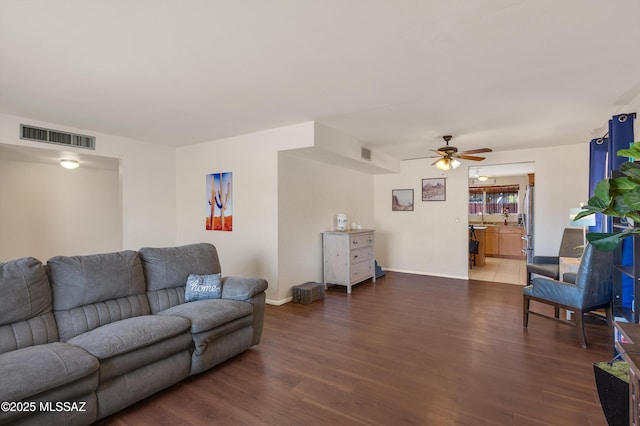 living area featuring baseboards, ceiling fan, visible vents, and wood finished floors