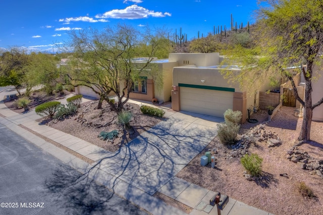 adobe home with concrete driveway, an attached garage, fence, and stucco siding