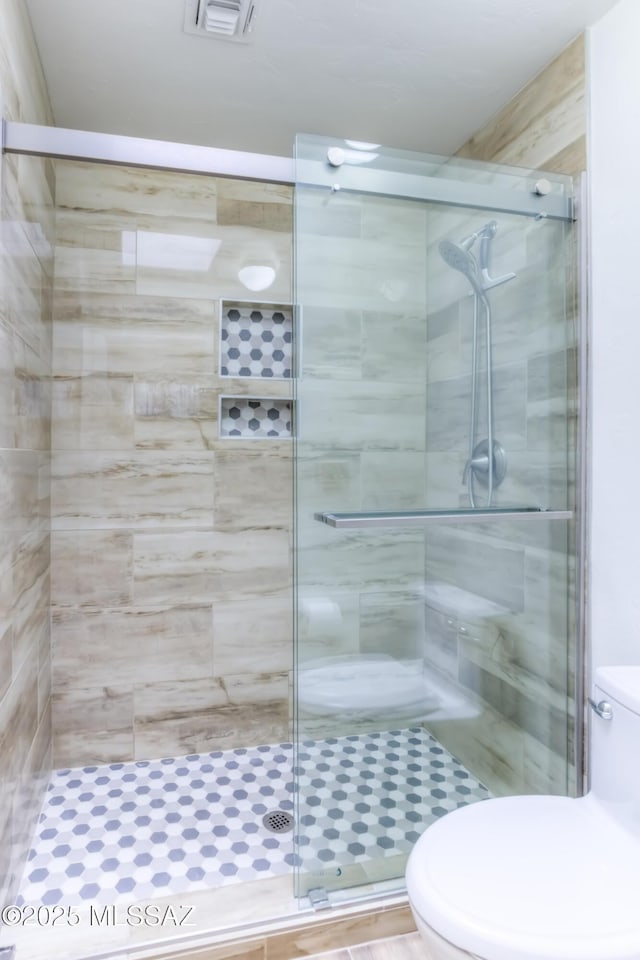 full bath with toilet, visible vents, and a stall shower