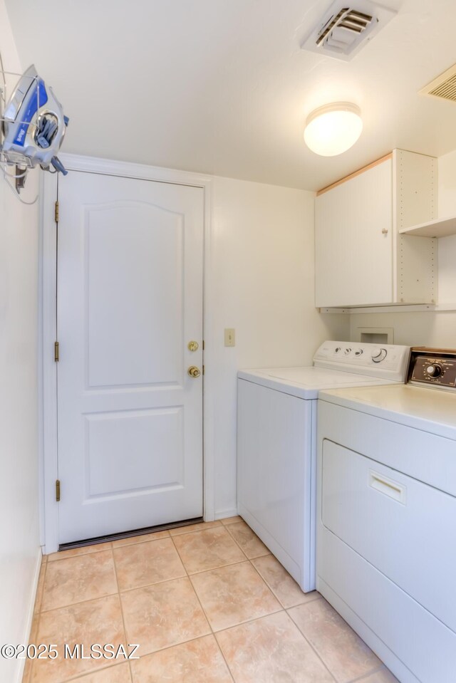 clothes washing area featuring washer and dryer, visible vents, laundry area, and light tile patterned floors