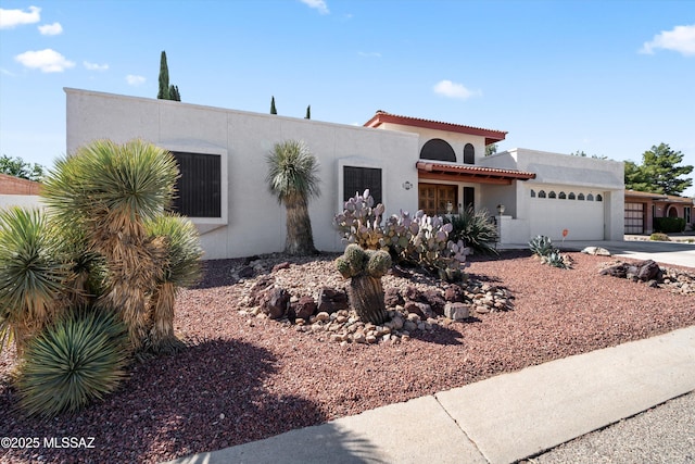 view of front of house featuring stucco siding, driveway, an attached garage, and a tiled roof