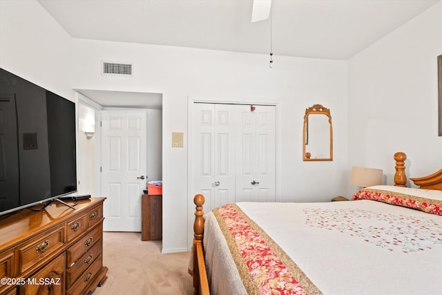 bedroom with visible vents, light colored carpet, a closet, and a ceiling fan