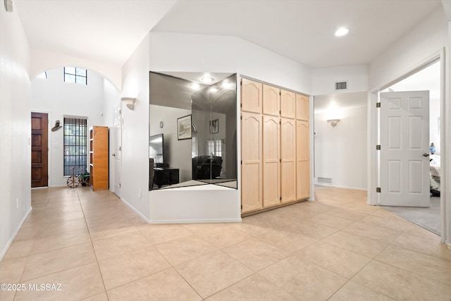 corridor featuring light tile patterned floors, visible vents, arched walkways, and baseboards