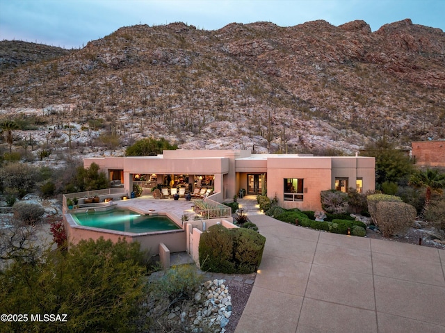 exterior space with a patio, an outdoor pool, a mountain view, and stucco siding