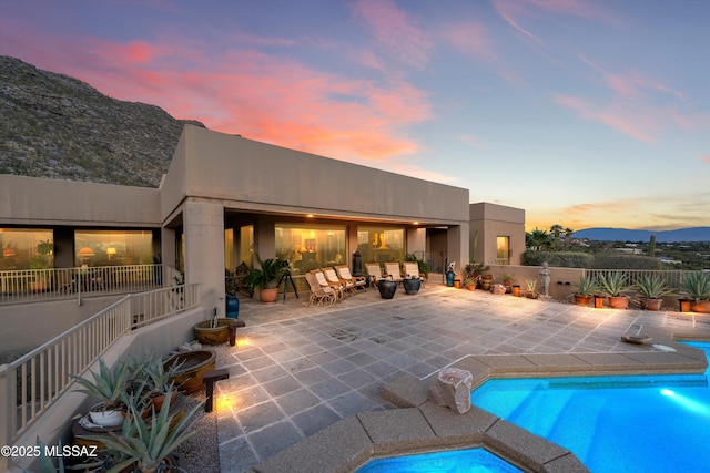 back of property featuring a fenced in pool, stucco siding, a patio, and a mountain view