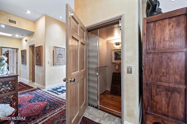 hallway featuring baseboards, elevator, visible vents, and recessed lighting