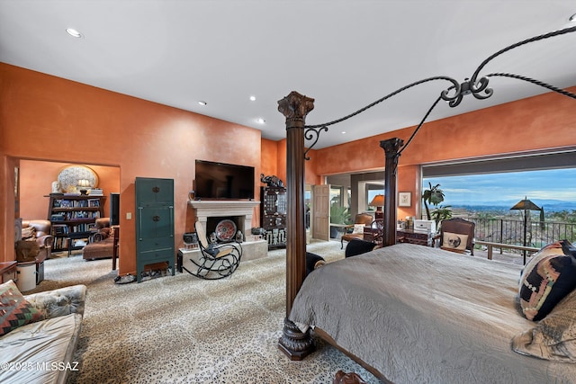 bedroom featuring access to exterior, recessed lighting, a fireplace with raised hearth, and ornate columns