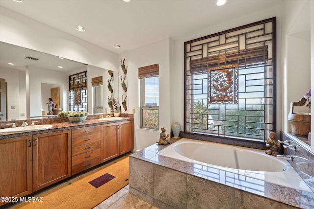 full bathroom featuring a bath, double vanity, a sink, and visible vents