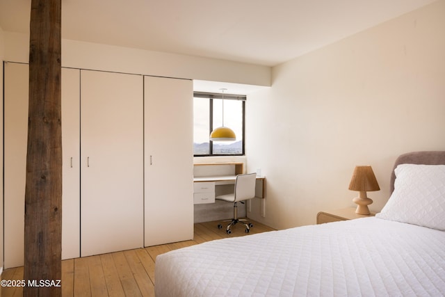 bedroom with hardwood / wood-style flooring, a closet, and built in desk