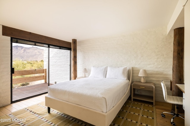 bedroom with access to exterior, multiple windows, a mountain view, and hardwood / wood-style flooring