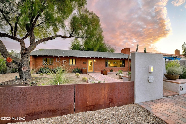 single story home with a fenced front yard, a chimney, and brick siding