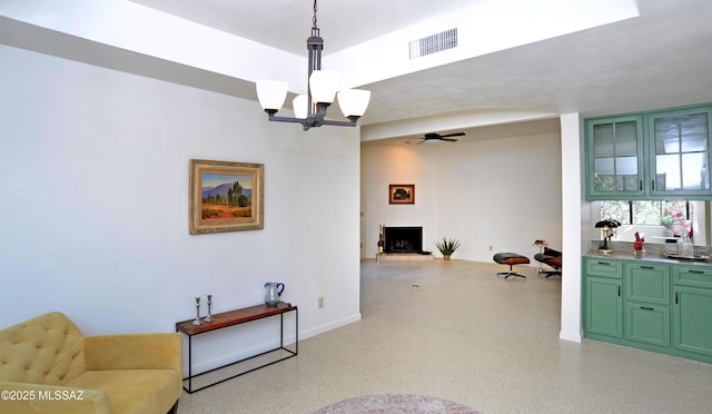 interior space with a large fireplace, visible vents, light speckled floor, and ceiling fan with notable chandelier