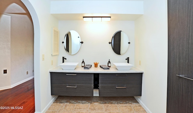 bathroom with double vanity, a sink, and baseboards