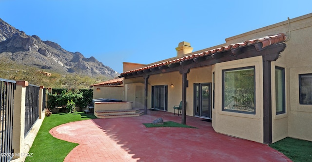 view of patio featuring a jacuzzi, a mountain view, and a fenced backyard