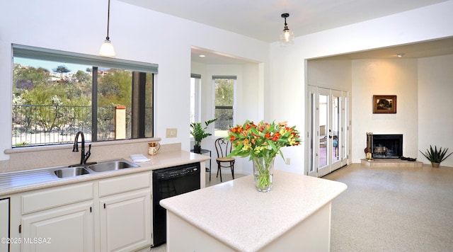 kitchen featuring black dishwasher, a fireplace with raised hearth, a sink, and light countertops