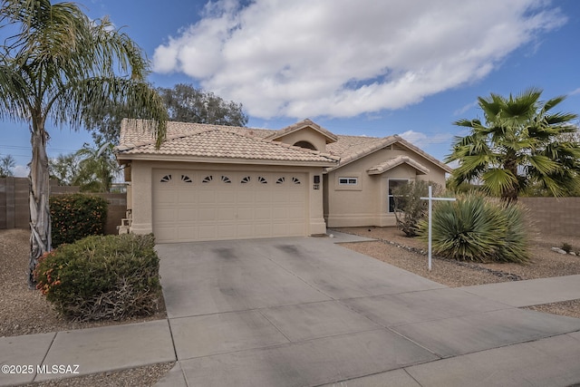 view of front of property featuring concrete driveway, a tile roof, an attached garage, fence, and stucco siding