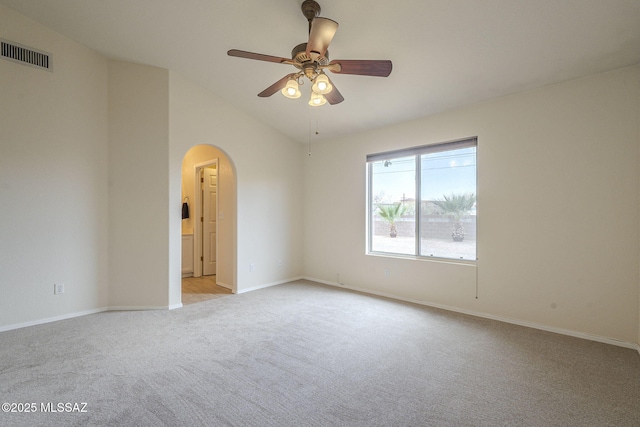 unfurnished room featuring lofted ceiling, visible vents, arched walkways, and light colored carpet