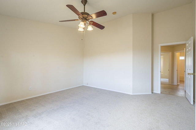 unfurnished room with a towering ceiling, a ceiling fan, baseboards, and carpet flooring